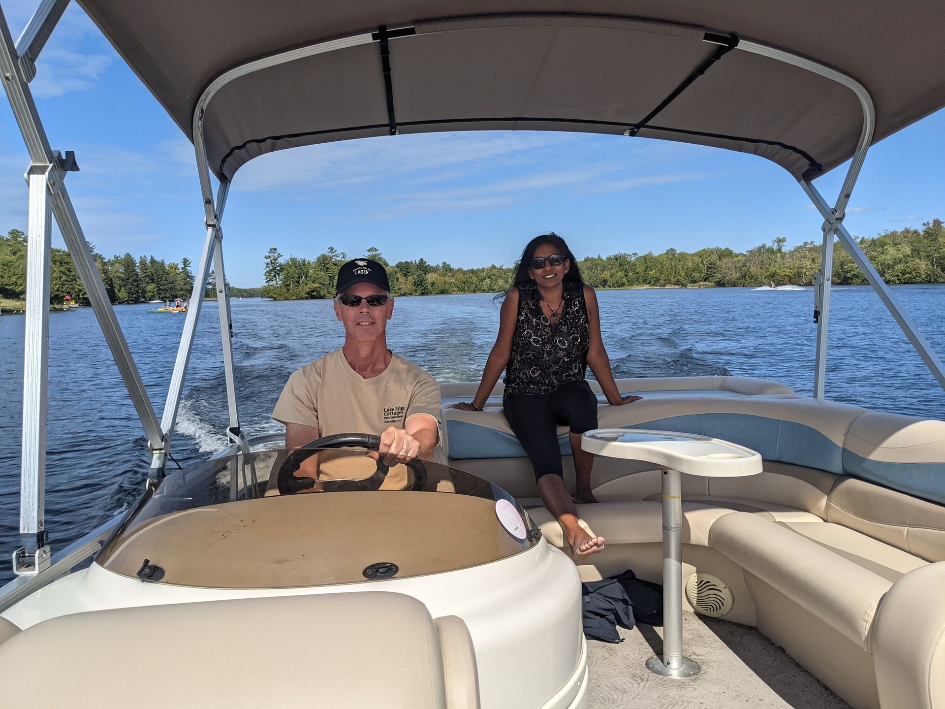 A man and a woman are sitting on a pontoon boat on a lake.