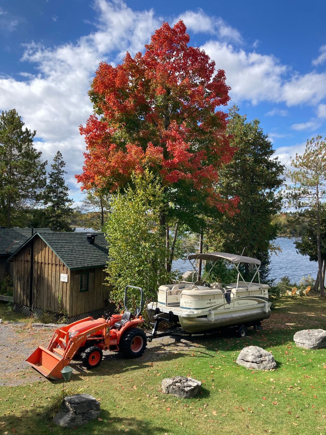 A tractor is pulling a pontoon boat on a trailer.