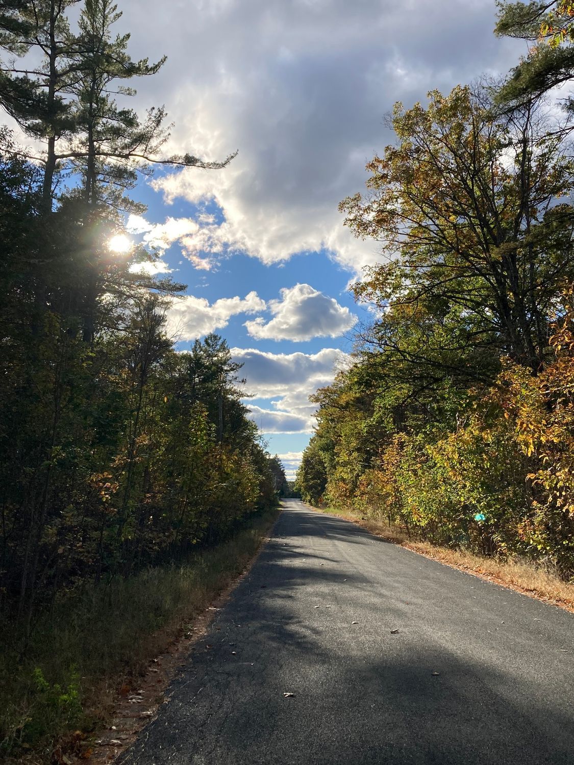 The sun is shining through the clouds over the road