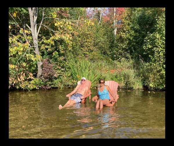 A man and a woman are sitting in chairs in the water.