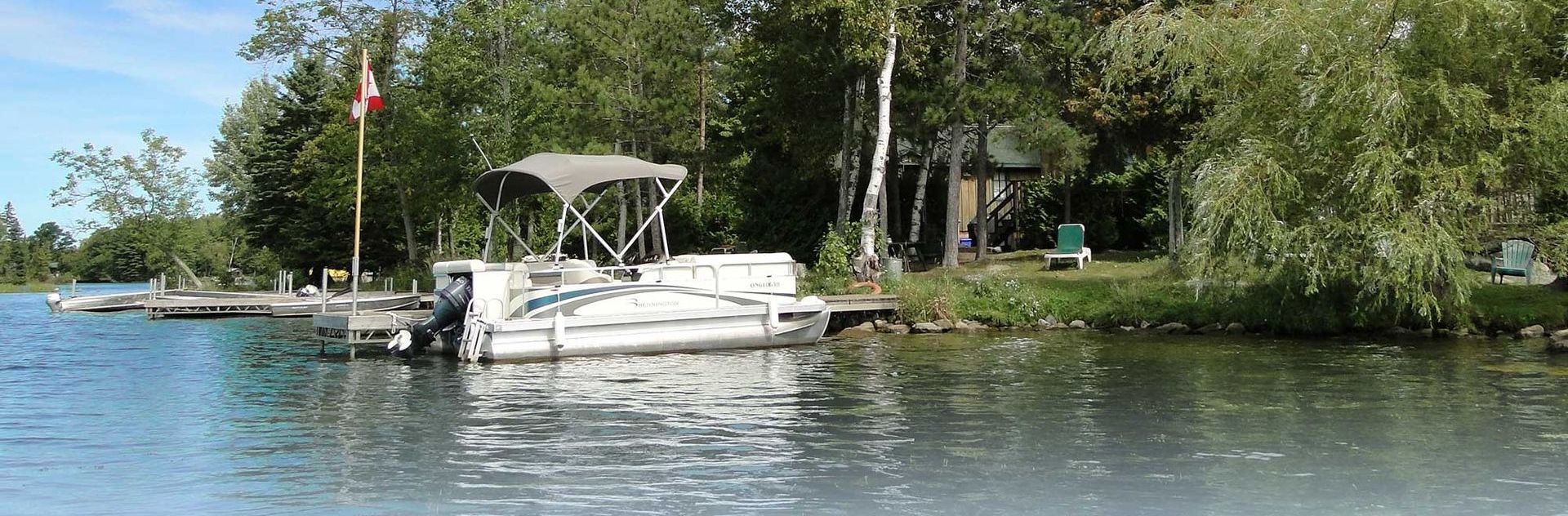 A boat is docked at a dock on a lake surrounded by trees.