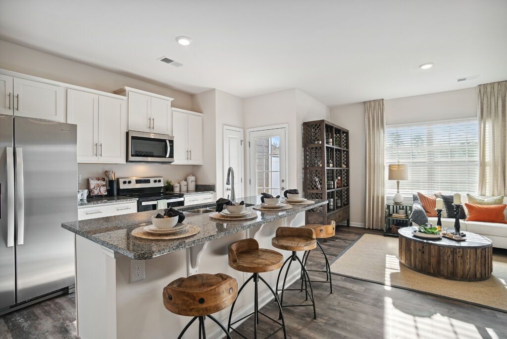 Modern kitchen with a breakfast bar, stainless steel appliances, and a living area.