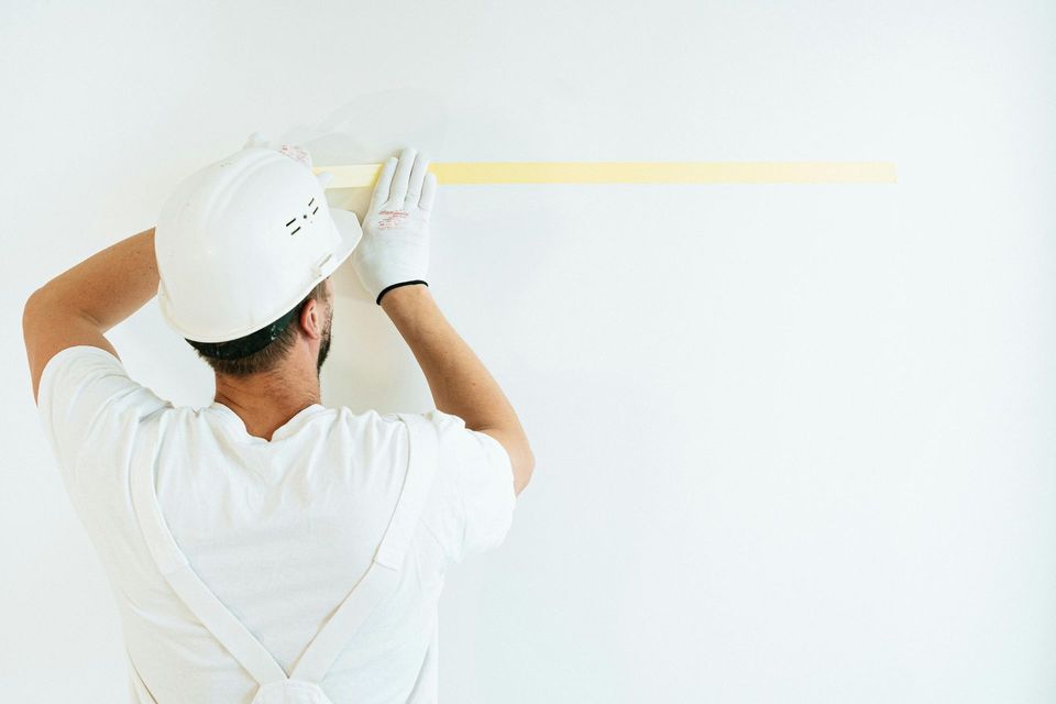 Professional painter in Zephyrhills FL applying wall tape for sharp clean paint lines and flawless finish for interior walls