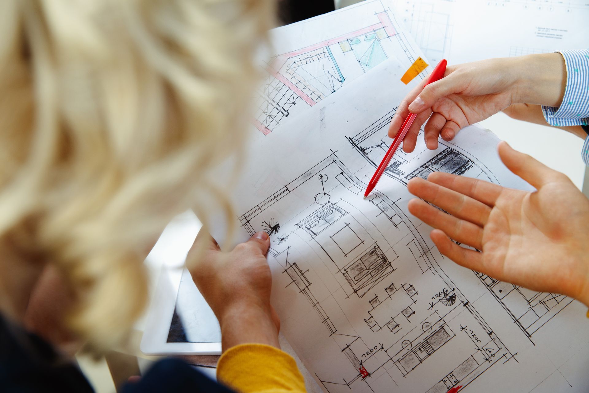 Two individuals reviewing architectural blueprints on a table, focused on enhancing property resale