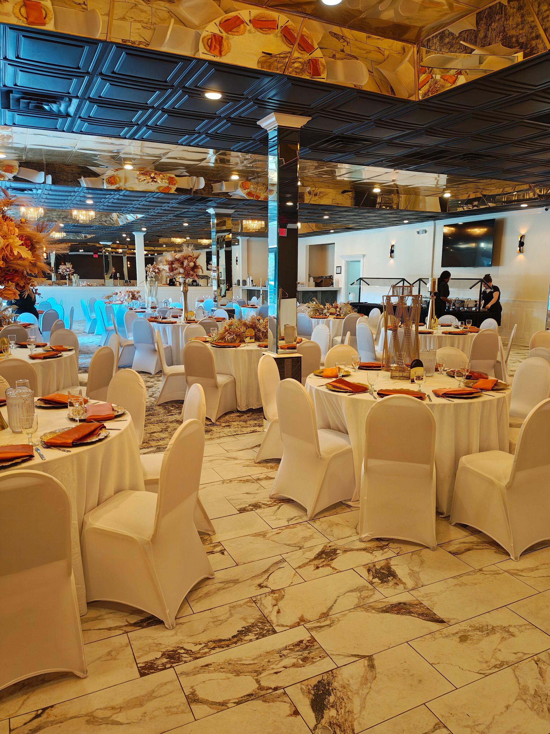 A table with three cakes on it and a woman taking a picture