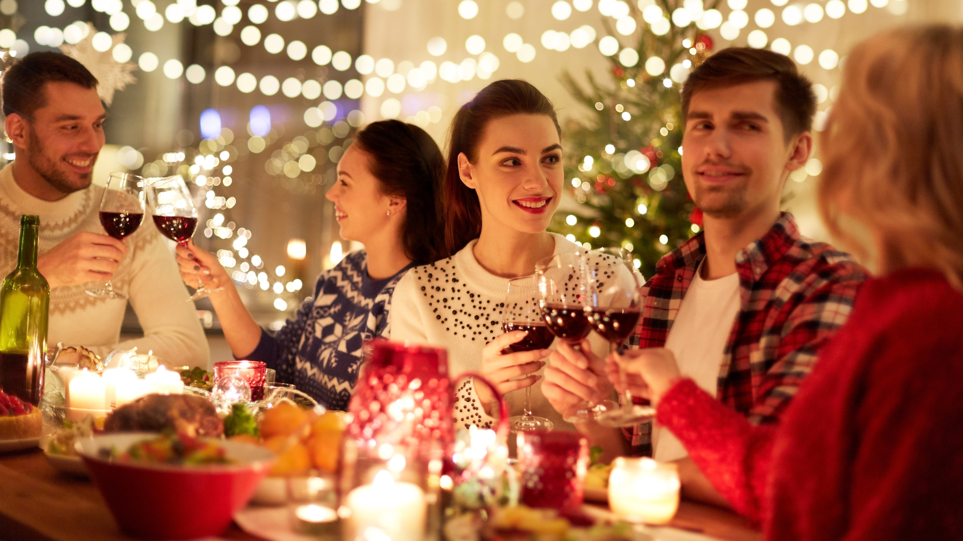 A group of people are sitting at a table toasting with wine glasses