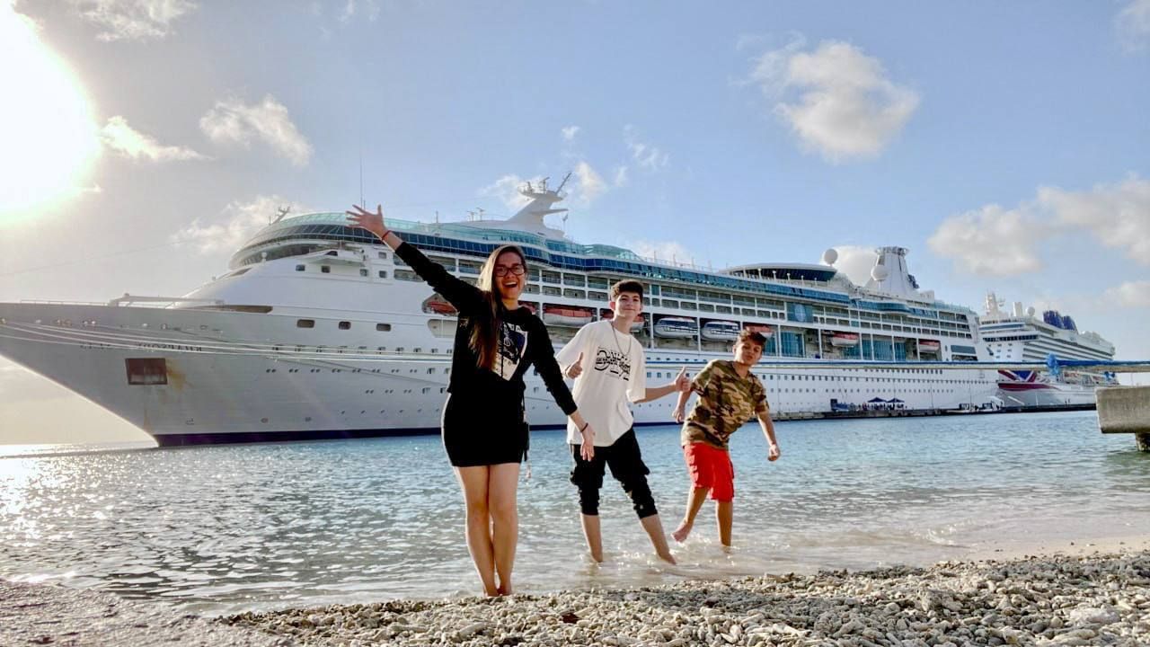 Una familia está parada en una playa frente a un crucero.