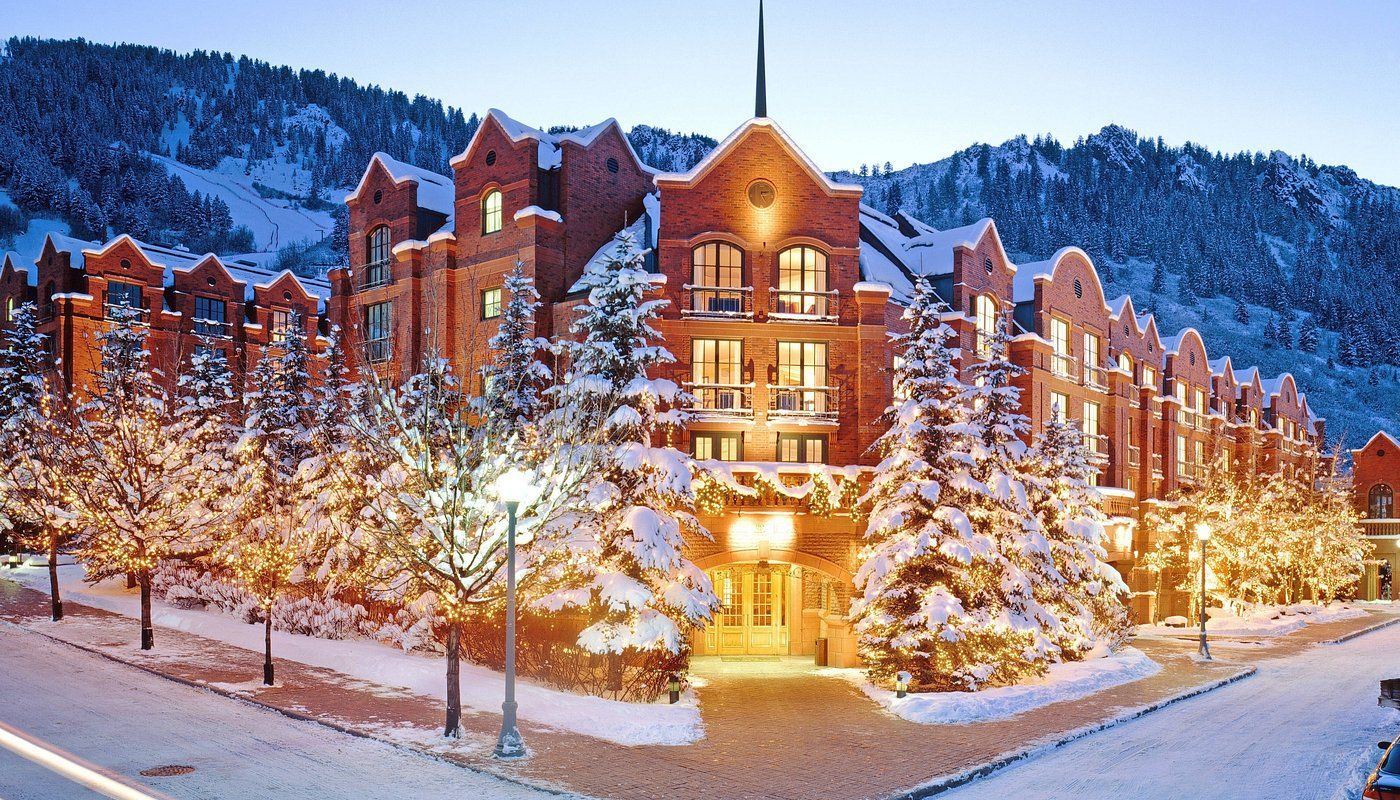 A large brick building is surrounded by snow covered trees