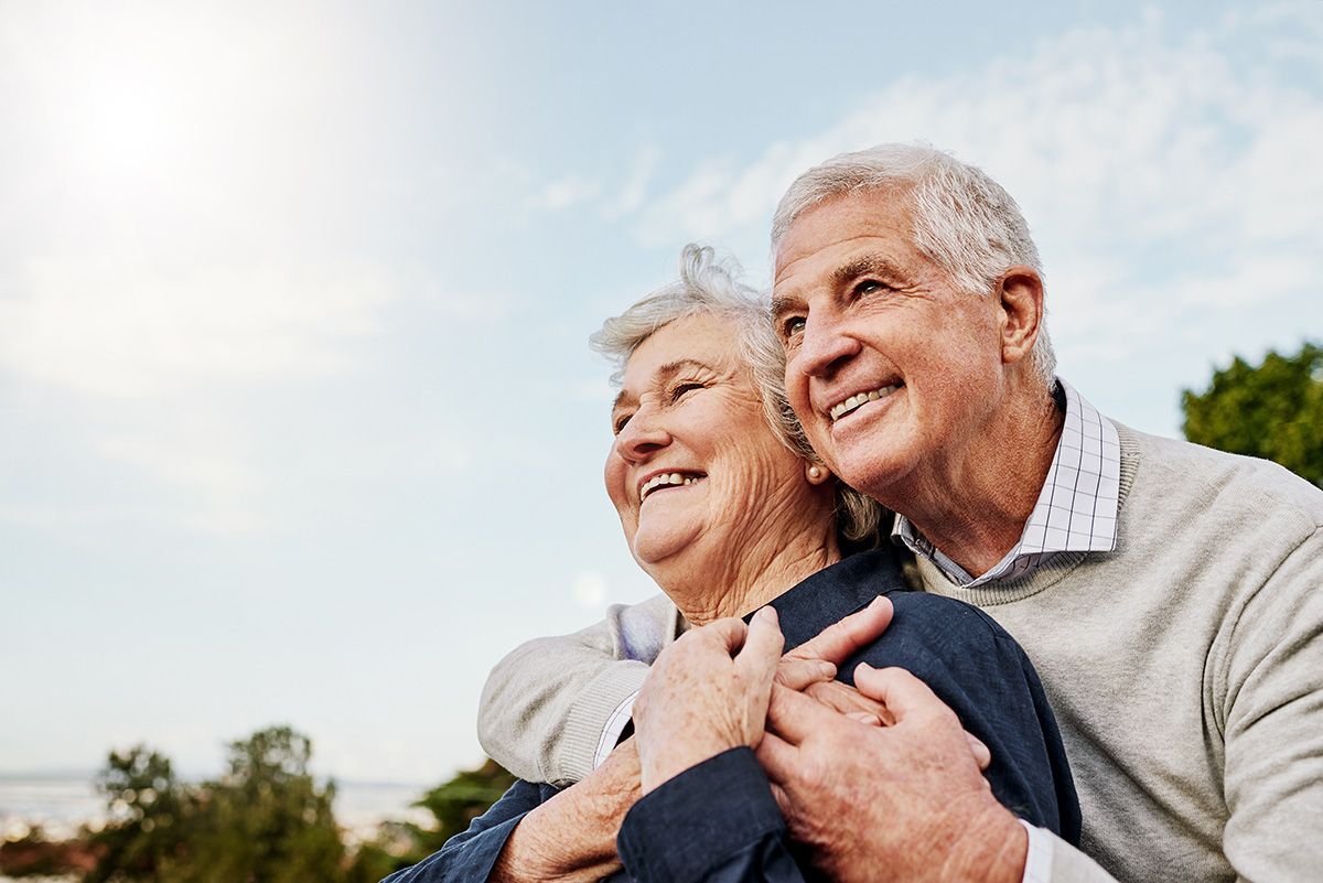 Smiling couple embracing outdoors under a bright sky