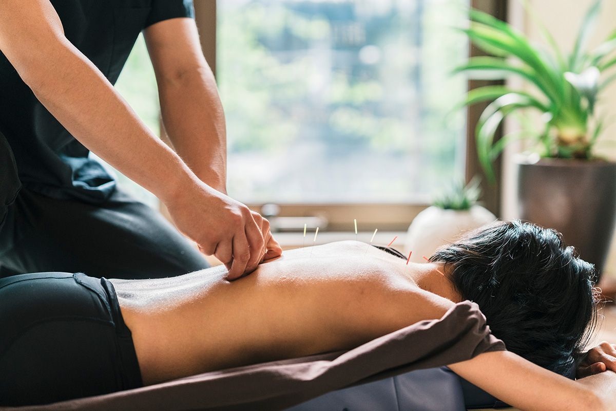 Massage therapist working on a client’s back in a bright spa room