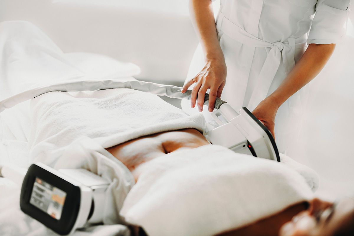Person receiving a body contouring treatment with a handheld device in a bright spa-like setting