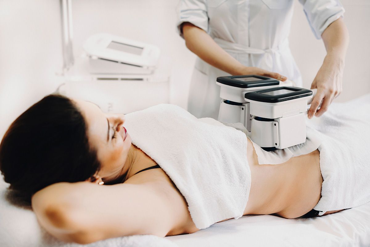 Woman receiving a body contouring treatment on her abdomen in a spa room