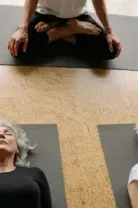 Three people lying on yoga mats in a studio, resting in a relaxed pose.
