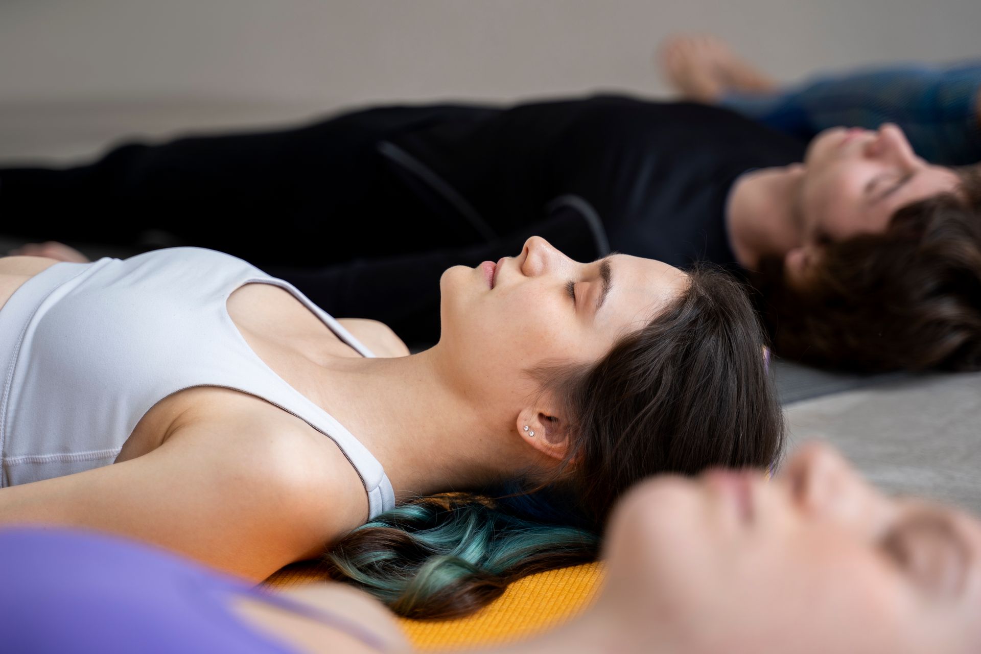 People lying on yoga mats in a relaxed pose during a group meditation class