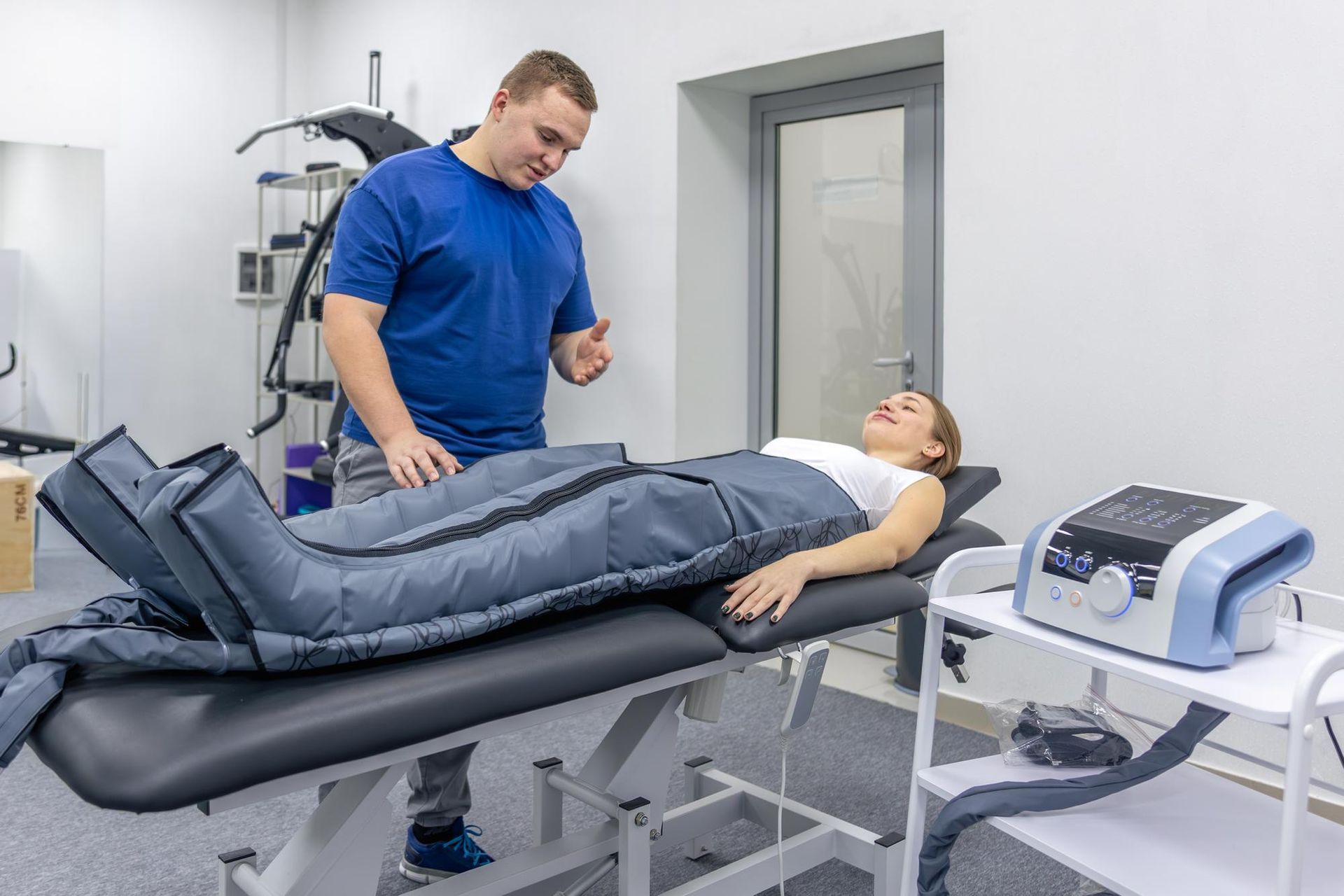 Therapy room with clinician adjusting a patient’s leg compression boots on a treatment table