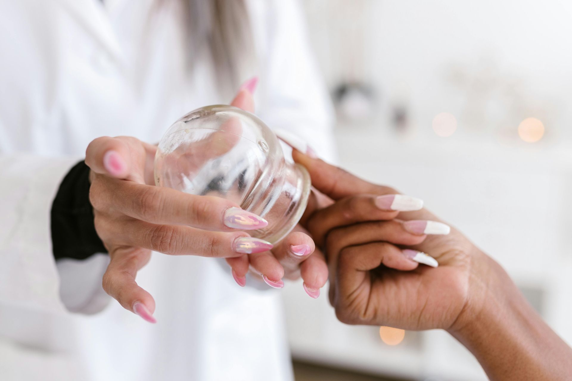 Hands receiving a clear dropper bottle during a skincare application on a white background