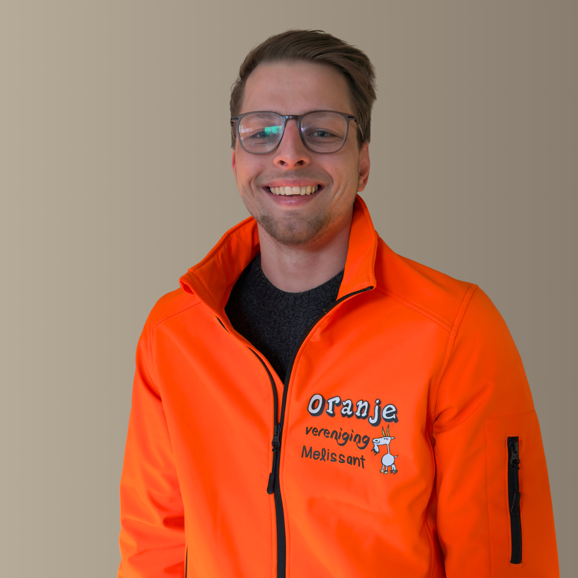 Een lachende man met een bril en een oranje jas met de opdruk 
