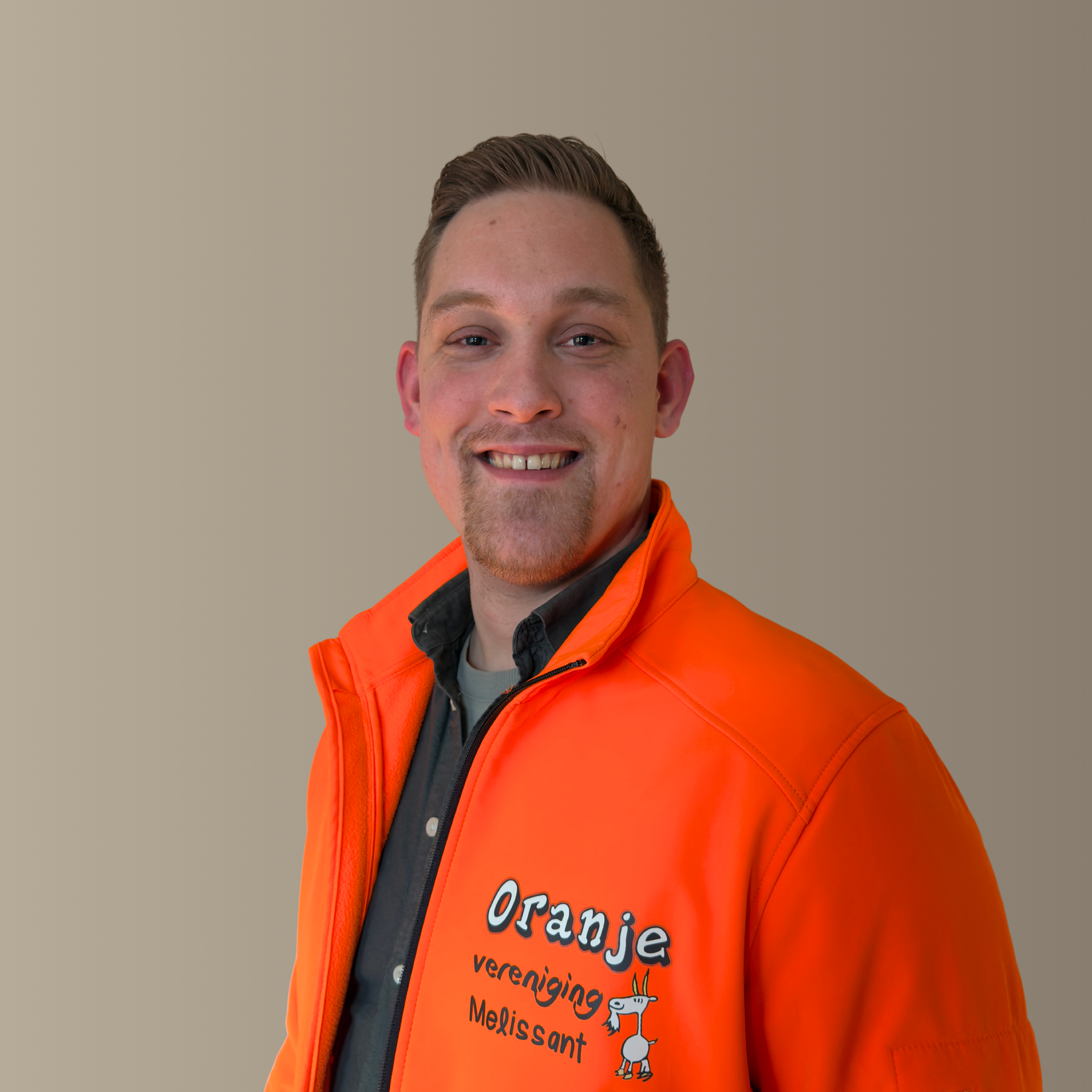 Man wearing an orange jacket smiling; jacket reads 