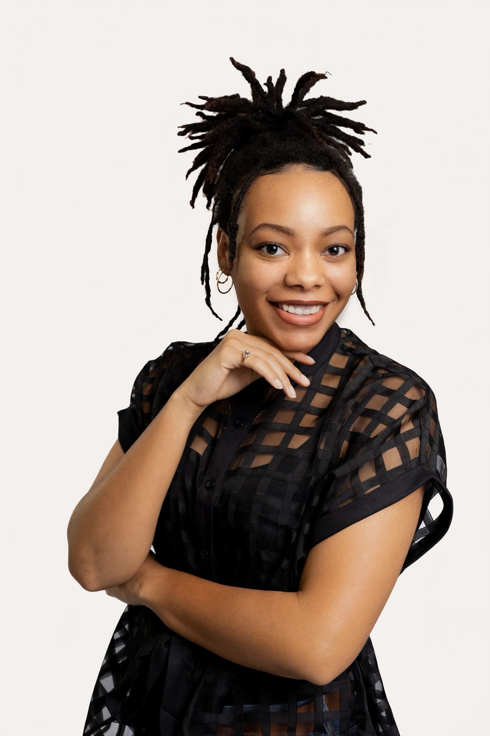 A woman is sitting at a desk with a laptop and a vase of flowers.