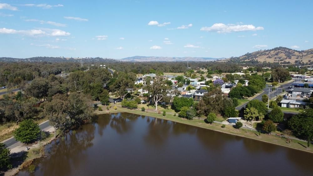 An Aerial View Of A Lake Surrounded By Trees And Houses — Custom Air In Wodonga, NSW
