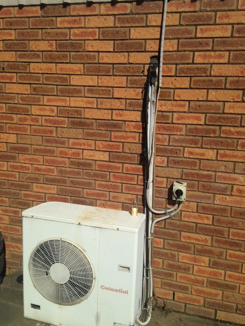 A Brick Wall With An Air Conditioner Attached To It — Custom Air In East Albury, NSW