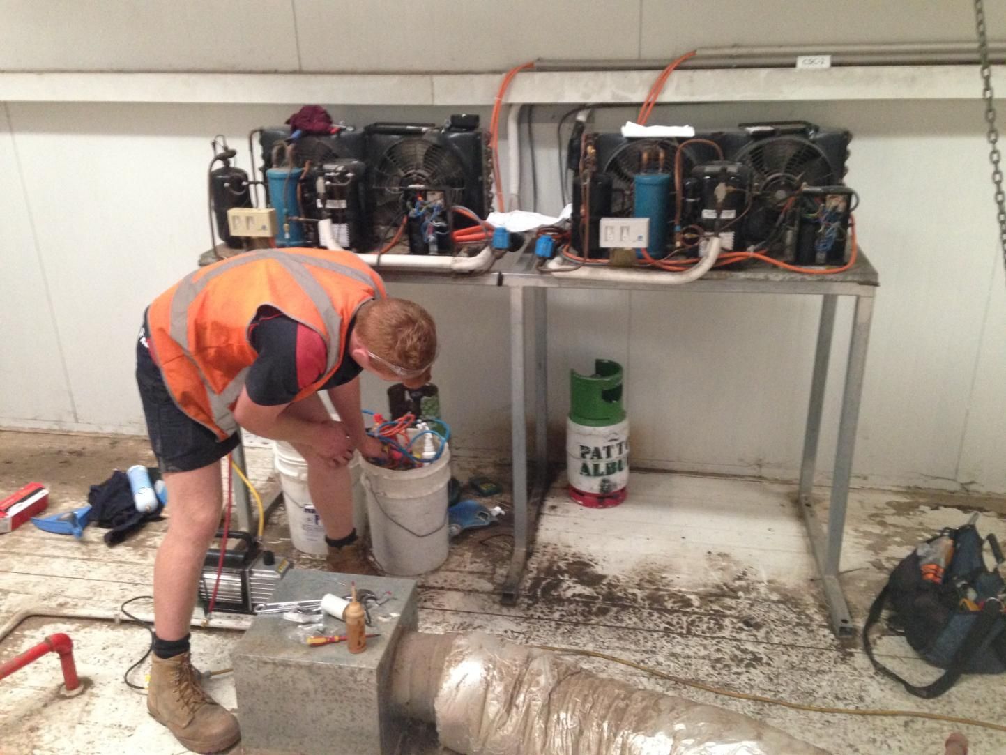 A Man In An Orange Vest Is Working On An Air Condition — Custom Air In Albury, NSW