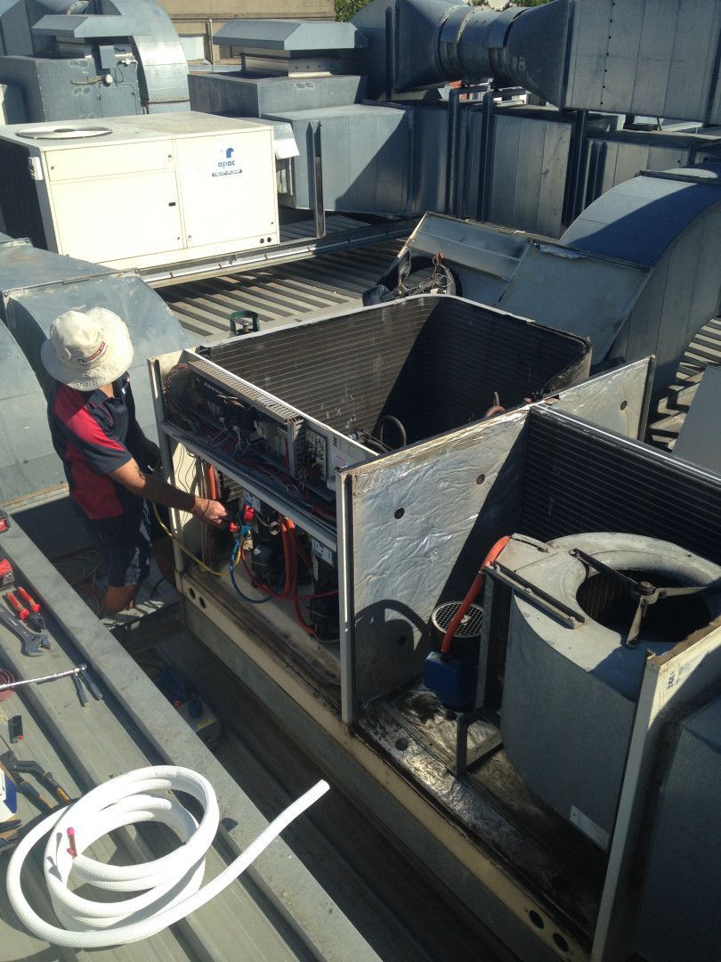 Man On Rooftop Servicing Air Conditioning Unit— Custom Air In East Albury, NSW