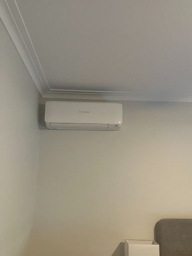 A White Air Conditioner Is Hanging From The Ceiling In A Living Room — Custom Air In East Albury, NSW