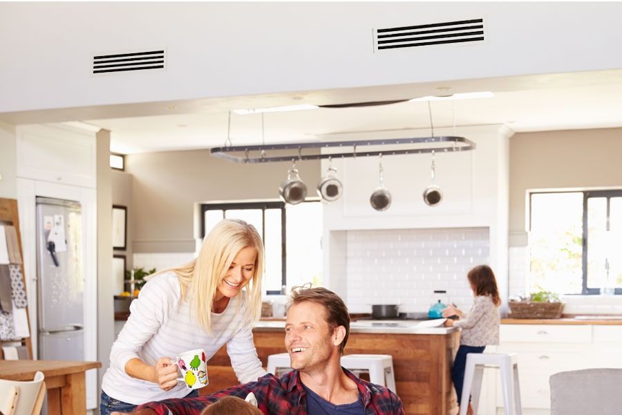 A Woman Is Serving A Cup Of Coffee To A Man In A Kitchen — Custom Air In Towong, NSW