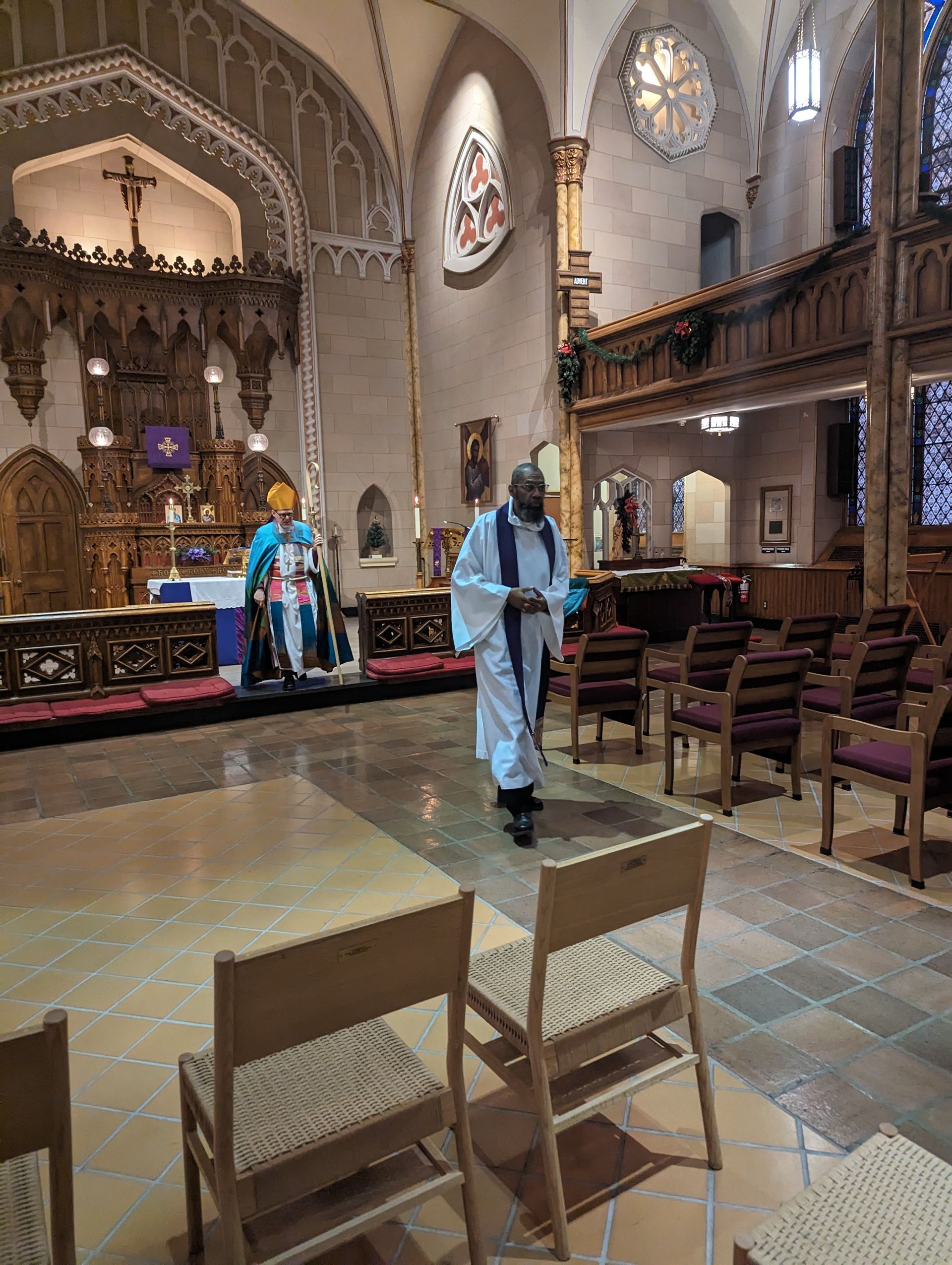 Bp. Lane and Rev. Patterson in church, one at altar, the other walking aisle, empty chairs.