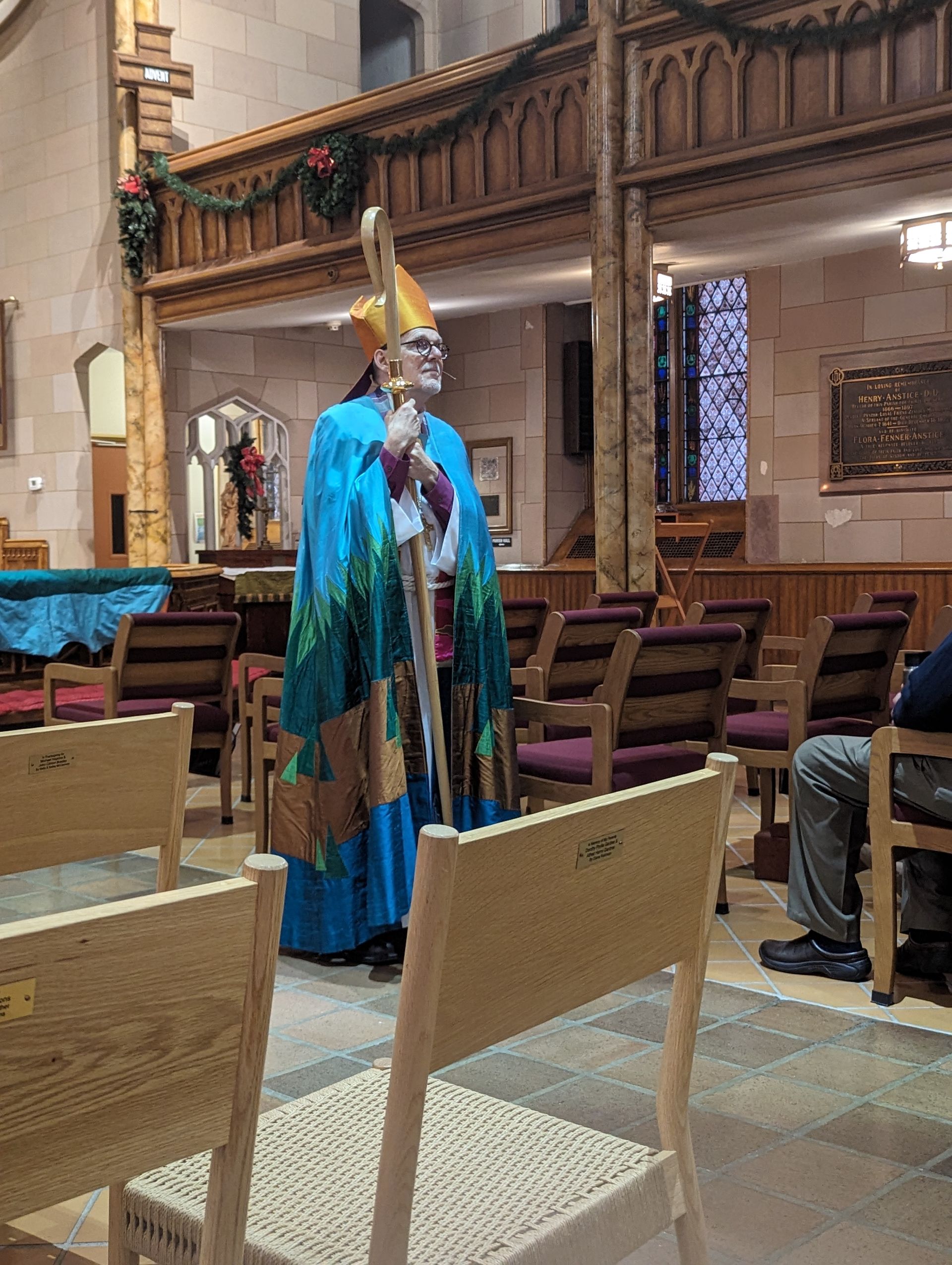 Bishop Stephen Lane in blue and green vestments, holding crozier, inside a church.