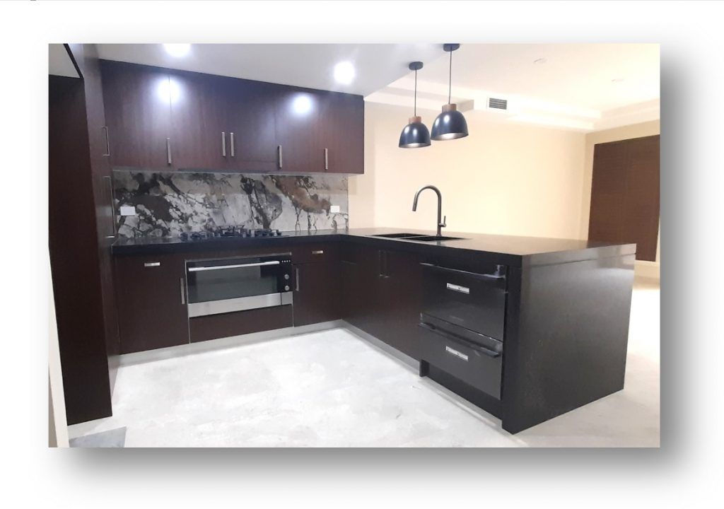 A kitchen with a black counter top and white cabinets A kitchen with a sink , cabinets , and a window.