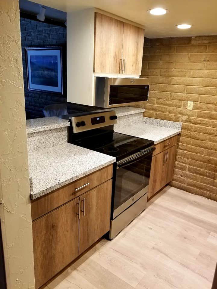 Modern kitchen featuring granite countertops and a rustic brick wall.
