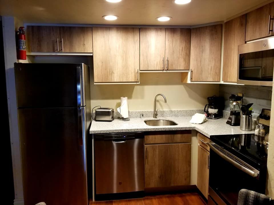 Modern kitchen featuring wooden cabinetry and a black fridge.