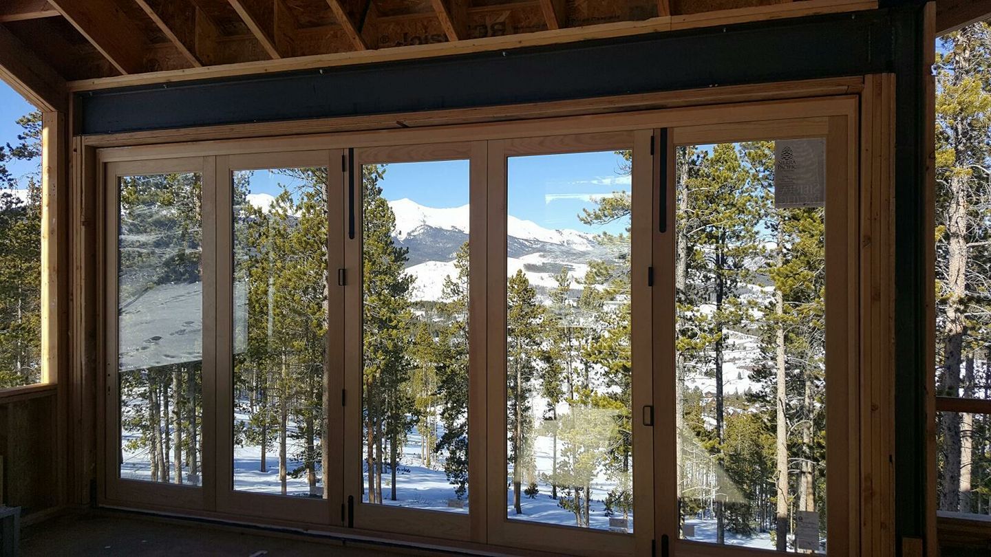 A room with a lot of windows and trees in the background.