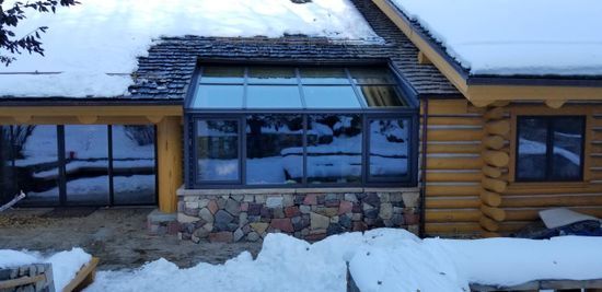 Aerial view of a log cabin covered in snow during winter season.