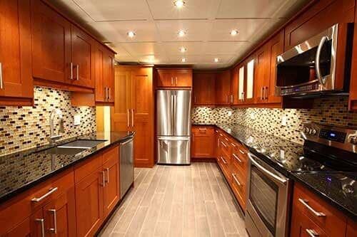 Modern kitchen with brown cabinets and a centrally placed stainless steel refrigerator.