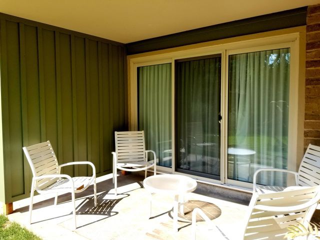 A green wall design patio with chairs and a table in front of a sliding glass door