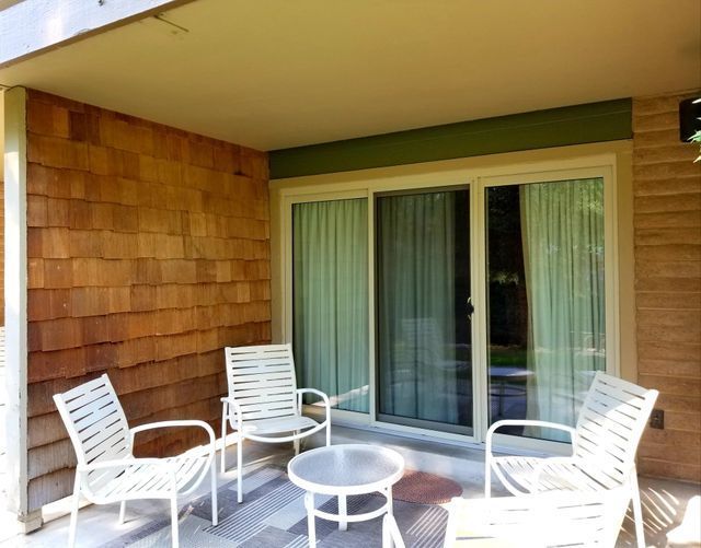 A brick-patterned wall patio with chairs and a table in front of a sliding glass door