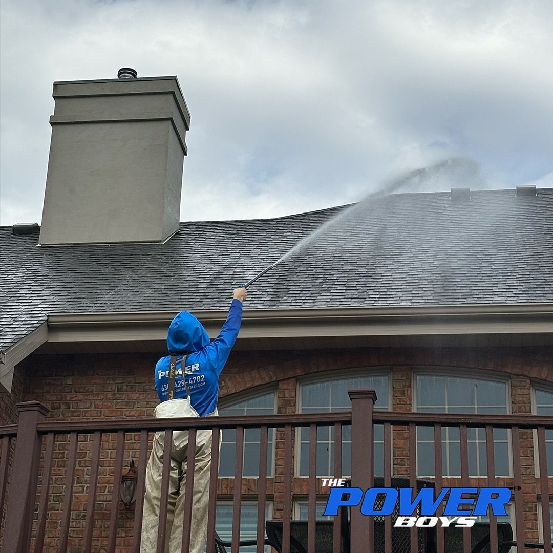 A person spraying water on a roof with the power boys logo in the background