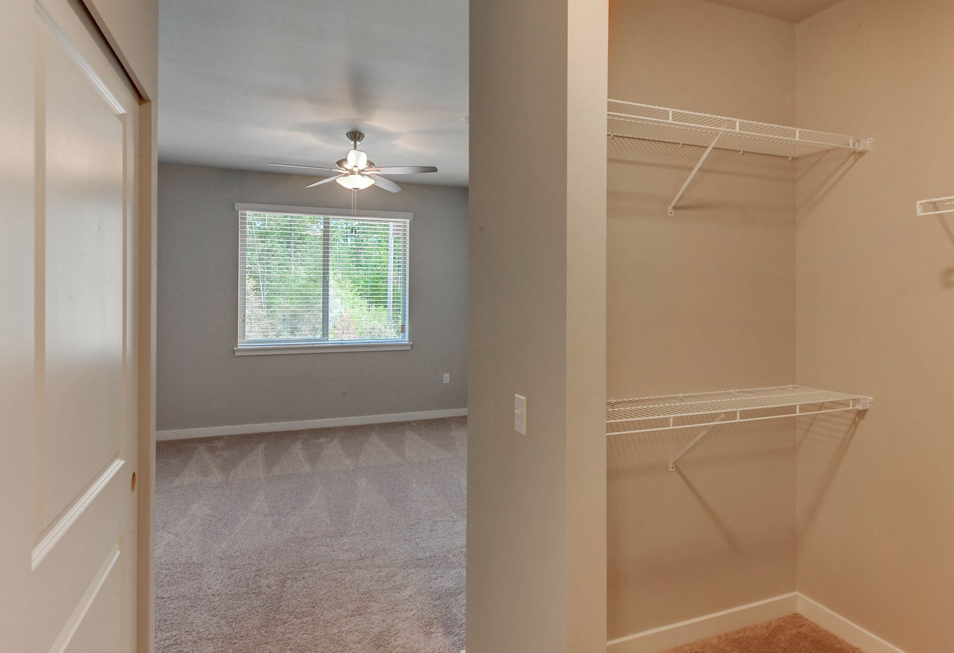 a walk in closet leading to a bedroom with a ceiling fan