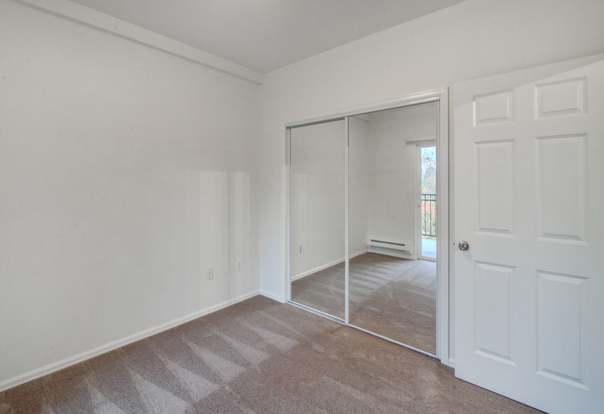 an empty bedroom with a large mirror in the closet .