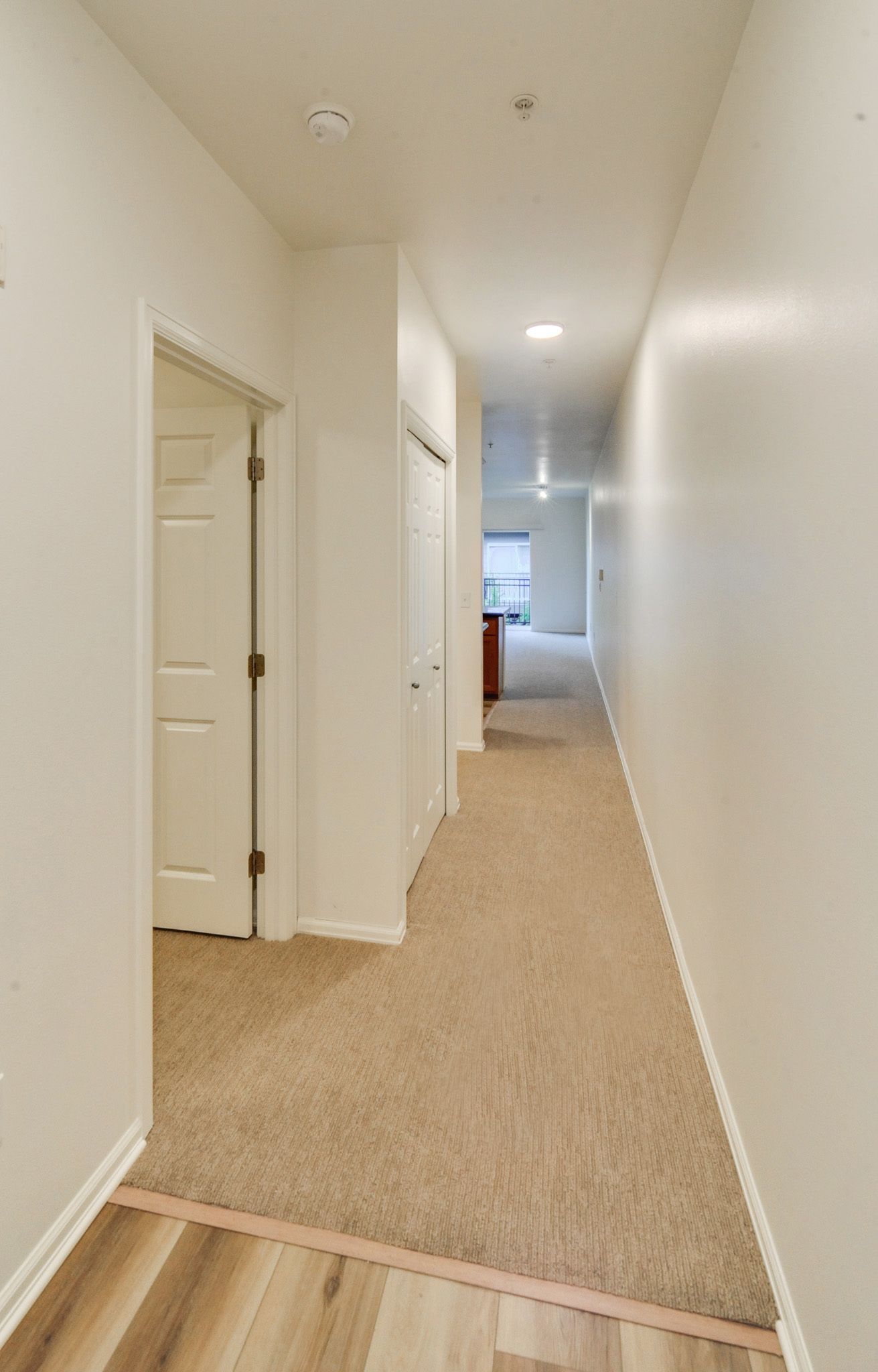 a long hallway with a wooden floor and a door in a house .