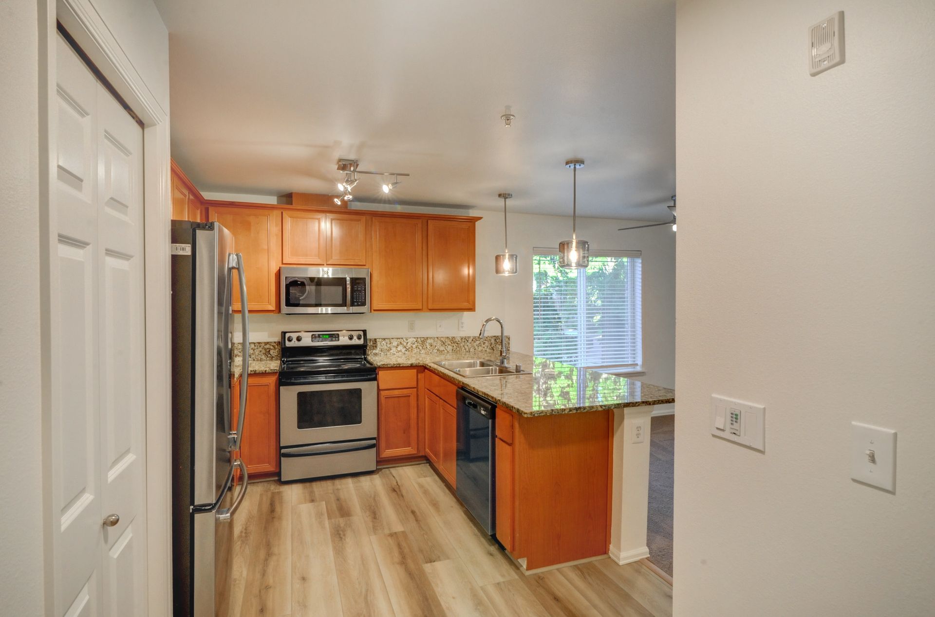 a kitchen with orange cabinets , stainless steel appliances , a refrigerator and a microwave .