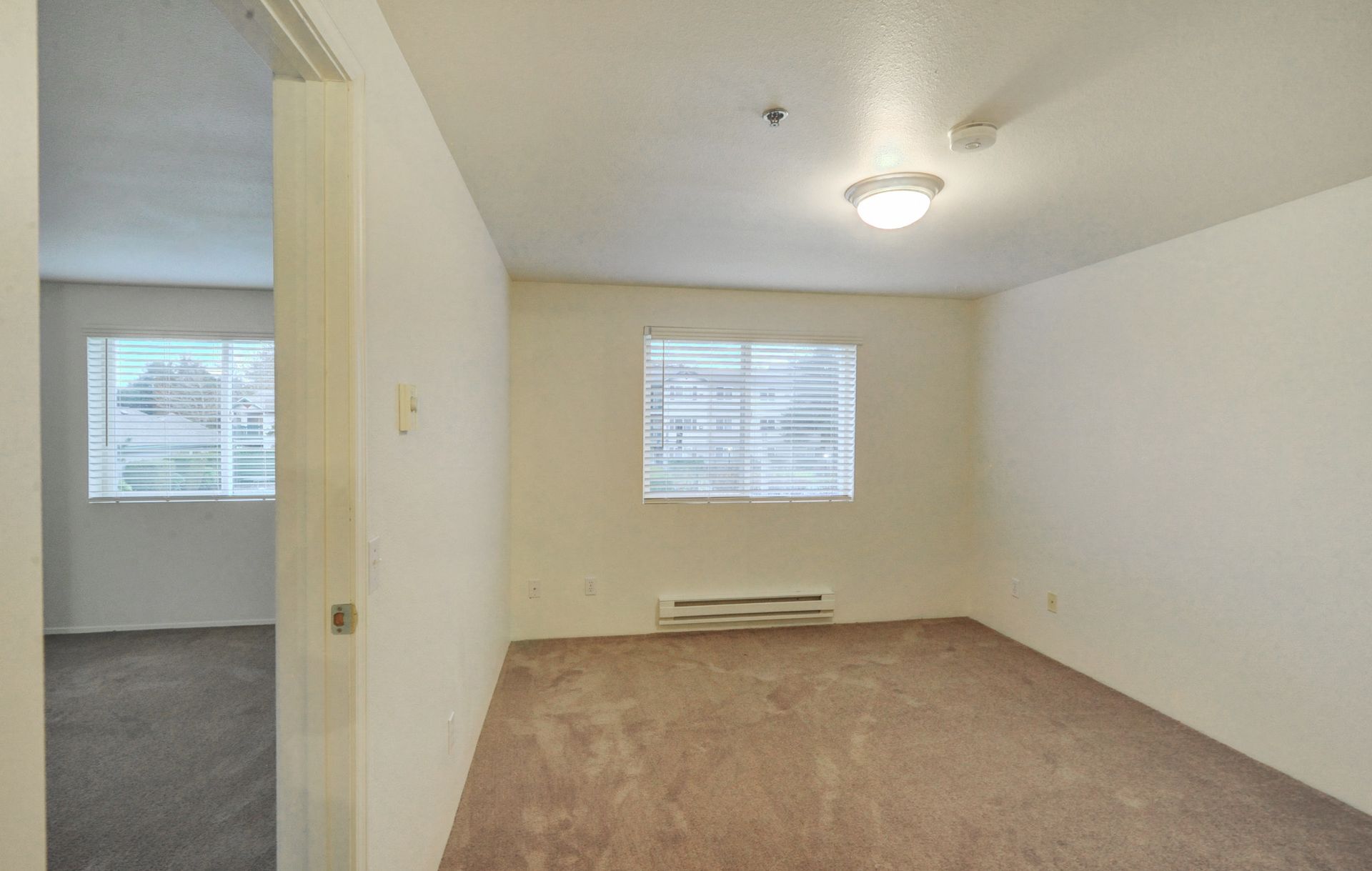 an empty bedroom with a window and a light on the ceiling