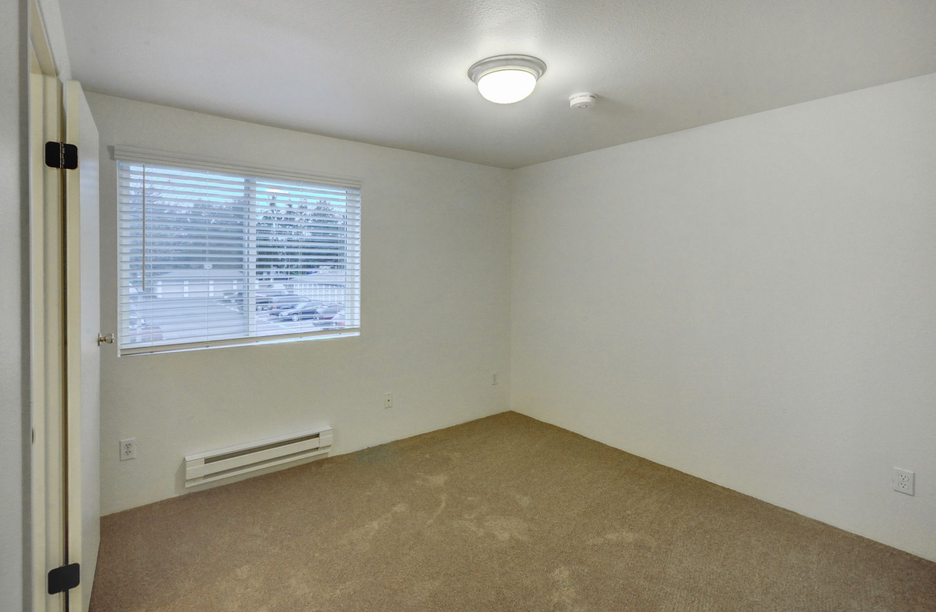 an empty bedroom with a window and blinds