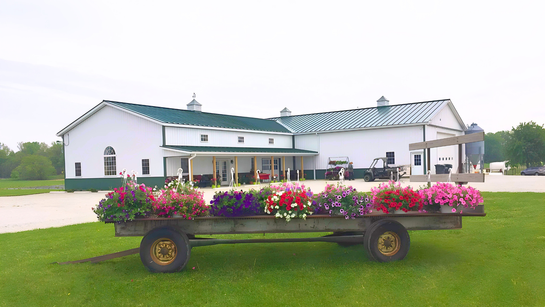 A wagon filled with flowers is parked in front of a building.