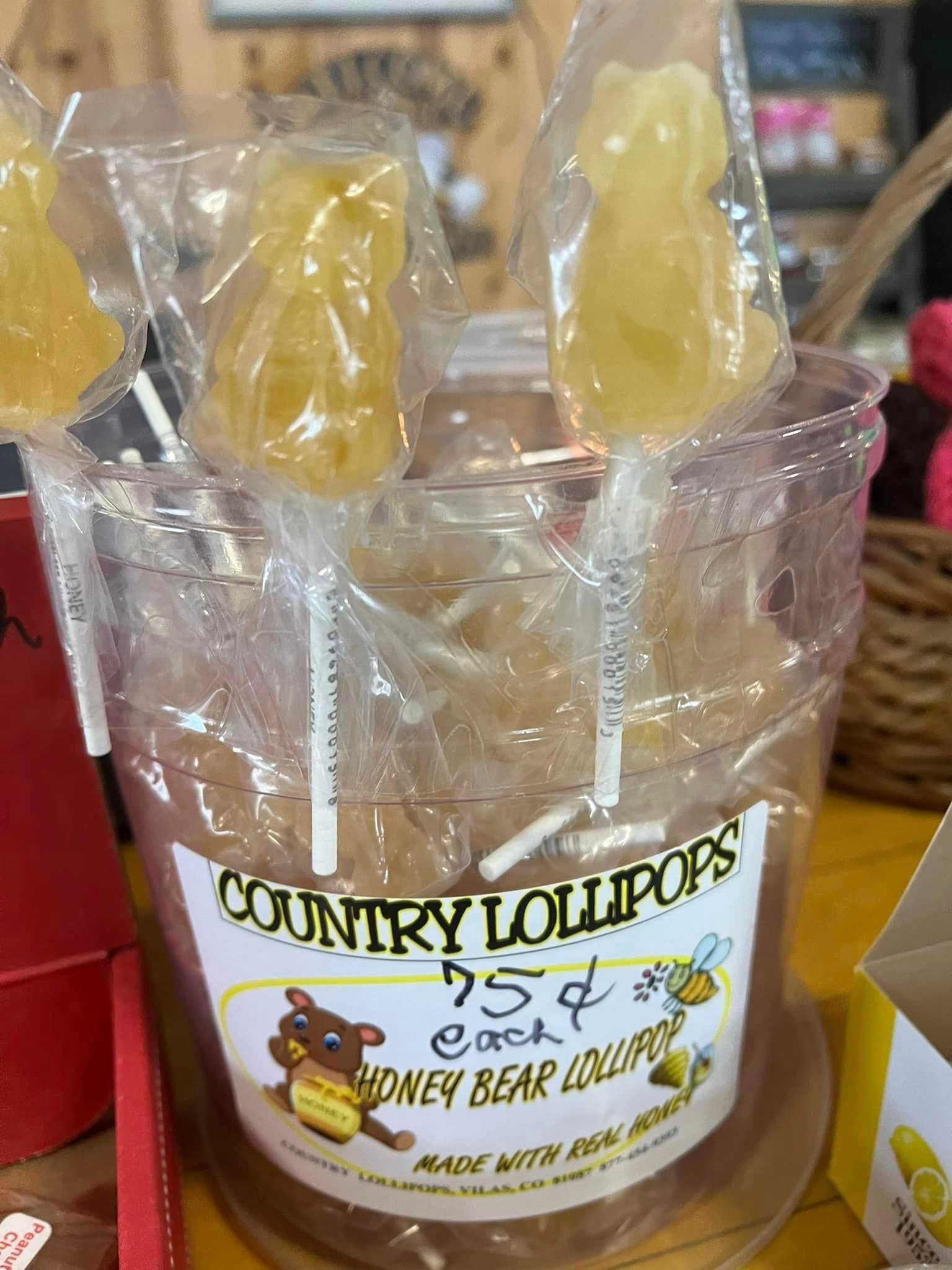 A bucket of honey bear lollipops is sitting on a table.
