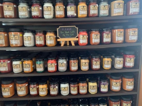 A shelf full of jars with a sign that says please do not lift by the lid