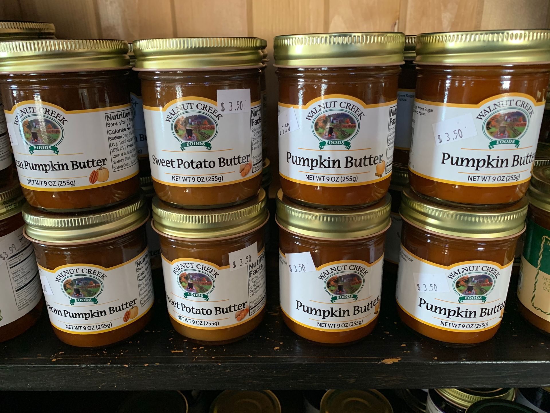 Several jars of pumpkin butter are stacked on top of each other on a shelf.